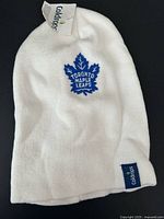 Full view of white Toronto Maple Leafs toque showing embroidered logo and overall condition