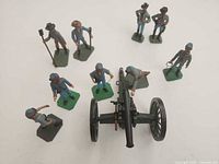 Top view of eight soldier figurines surrounding artillery cannon