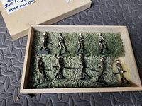 Box containing nine painted lead soldier figures on green knitted padding