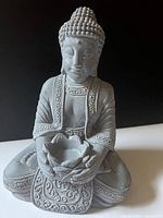 Front view of grey stone Buddha statue seated with lotus bowl