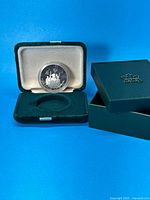 Coin in open velvet presentation box with outer box beside