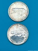 Two Canadian 25-cent Centennial coins, obverse sides not shown