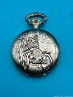 Front cover showing embossed antique car motif on silver-tone case