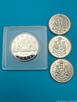 Group shot of 1972 dollar in case with three 50-cent coins