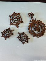 Group view of three turtle trivets and one round bird motif trivet