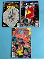 Group shot of three comic books: Adventures of Superman #499, Superman #75, Batman issue