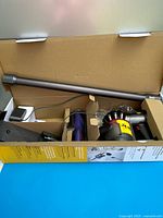 Box with vacuum body, extension wand and accessories visible