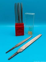 Group shot showing 11 needle files in red stand, two hand files and clear sleeve