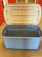 Full view of open Rubbermaid bin showing light blue base and white hinged lid