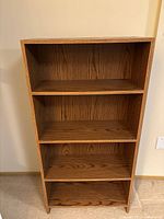 Full front view of medium brown 4-shelf wood bookshelf