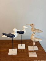 All four bird figurines on wooden table