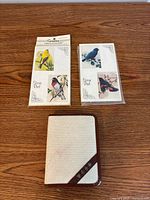 Two sealed bird score pads and fabric case displayed