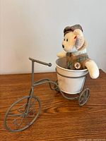 Bear seated in metal tricycle planter