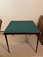 Full view of folded-out green vinyl card table with black metal legs