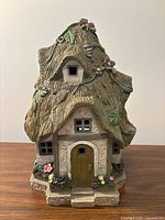 Front view of resin fairy cottage showing door, windows, roof detail and floral accents