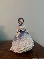 Front view of Royal Doulton Alice figurine showing gown, bonnet and coloration