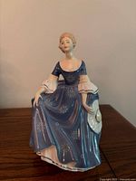 Front view of Royal Doulton Hilary figurine showing blue gown and white hat