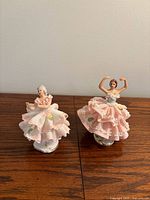Both porcelain dancing girl figurines standing side by side on wooden surface