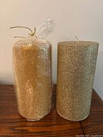 Both gold glitter pillar candles side by side, one wrapped, one unwrapped