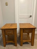 Front view of both oak veneer end tables showing drawers and shelves