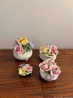 All four porcelain flower arrangements on wooden surface