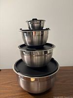 Stack of four stainless steel bowls with lids, nested largest to smallest