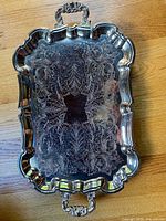 Top view of silver plated footed tray showing engraved surface and ornate handles