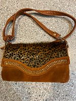 Full view of handbag showing faux fur flap, suede body, strap