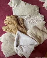 Pile of six linens showing different crochet styles and plain cloths
