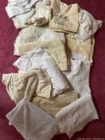 Pile of assorted lace and linen tablecloths and napkins in white, cream and ivory shades