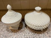 Two milk glass hobnail covered candy dishes side by side