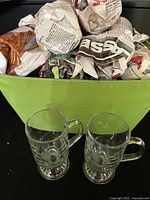 Green storage bin with wrapped mugs and two unwrapped Princess House Heritage Irish coffee mugs