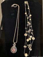 Both necklaces displayed: multi-strand WHBM and Avon pendant