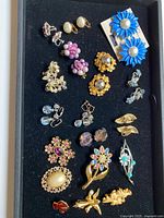 Overview of all earrings and brooches on black tray