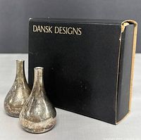 Pair of silverplated Danish candle holders beside original black box with 'DANSK DESIGNS' lettering.