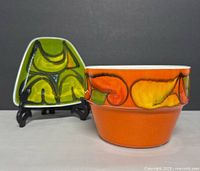 Photo showing the two vintage Poole Pottery dishes side by side against a grey background on display stands and surface.