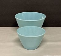 Two vintage Fire King nesting mixing bowls in blue, one large and one small, shown side by side