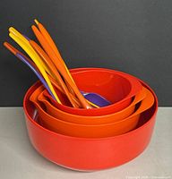 Three nesting melamine bowls and nine melamine utensils shown stacked neatly with varying colors.