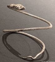 Silver plated coiled snake bangle with detailed snake head shown against a dark background for contrast.