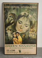Front view of framed Green Mansions film poster featuring Audrey Hepburn and Anthony Perkins with jungle scenes and animals, showing overall vintage condition.