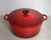 Top view of red enameled cast iron Dutch oven with lid and side handles