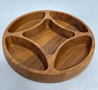 Top angle view showing four curved compartments surrounding a central square compartment in a round teak bowl.
