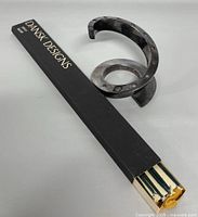 Photo showing the Dansk silver plated spiral taper candle holder alongside two black boxes labeled 'DANSK DESIGNS' containing green taper candles.