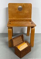 Front view showing kid size plywood chair with circular cutout backrest and oak card box with yellowed recipe cards.