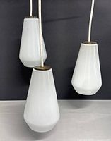 Center image showing three white drop-shaped glass shades suspended from white cords.