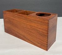 Front angled view of the teak desk organizer showing two rectangular compartments and one circular pen holder compartment with dovetail joinery.