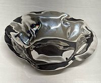 Front angle view showing the crumpled, reflective metal design and wavy edges.