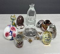 Full view of all ten art glass pieces on a white surface against a dark background showing variety of designs and colors.
