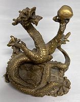 Front angle showing detailed dragon head, body scales, coiled posture, and sphere held in claw.