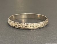 Front view of the hand chased silver bangle showing detailed floral and star designs.